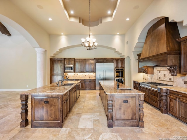 kitchen featuring pendant lighting, sink, built in appliances, and an island with sink