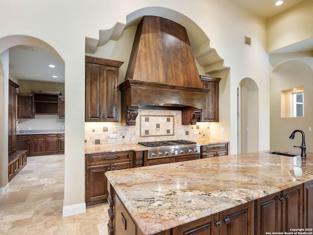 kitchen featuring sink, light stone countertops, custom range hood, and stainless steel gas stovetop