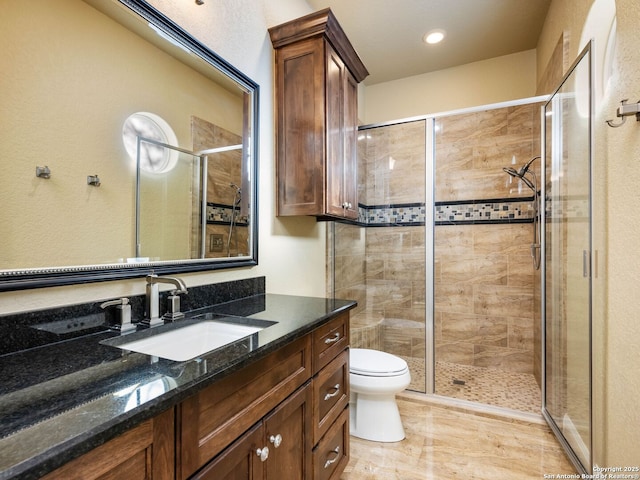 bathroom with vanity, a shower with door, and toilet