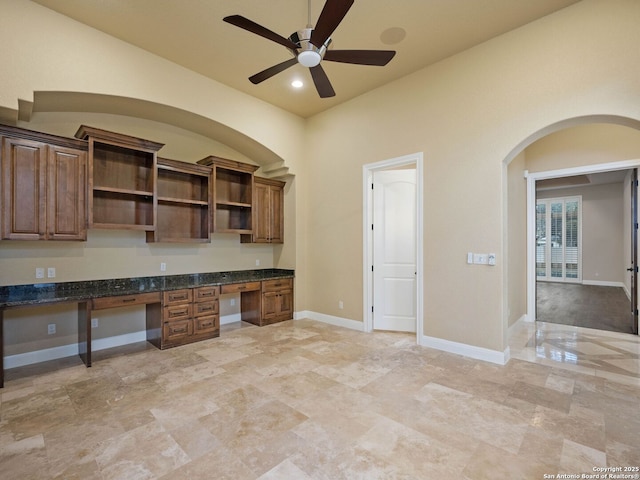 unfurnished office featuring built in desk and ceiling fan