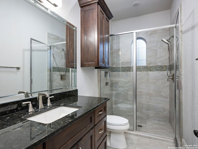 bathroom with vanity, a shower with door, and toilet