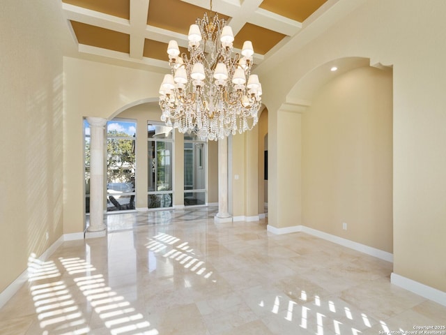 unfurnished dining area with coffered ceiling, an inviting chandelier, a towering ceiling, beam ceiling, and decorative columns