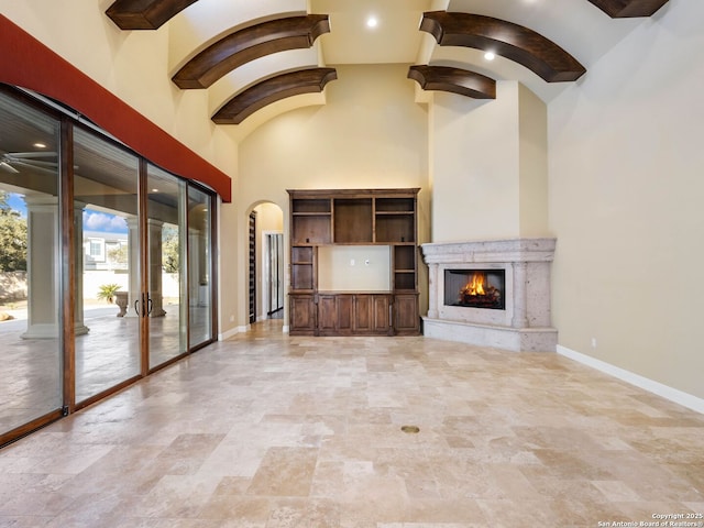 unfurnished living room with a towering ceiling and a high end fireplace