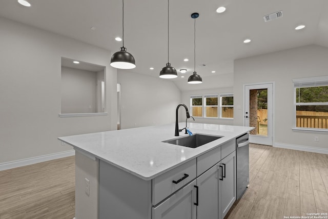 kitchen featuring decorative light fixtures, an island with sink, sink, stainless steel dishwasher, and light stone counters