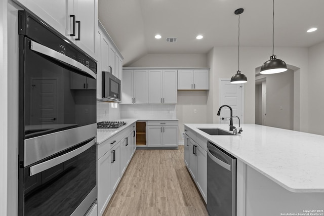 kitchen featuring tasteful backsplash, white cabinetry, sink, stainless steel appliances, and a center island with sink