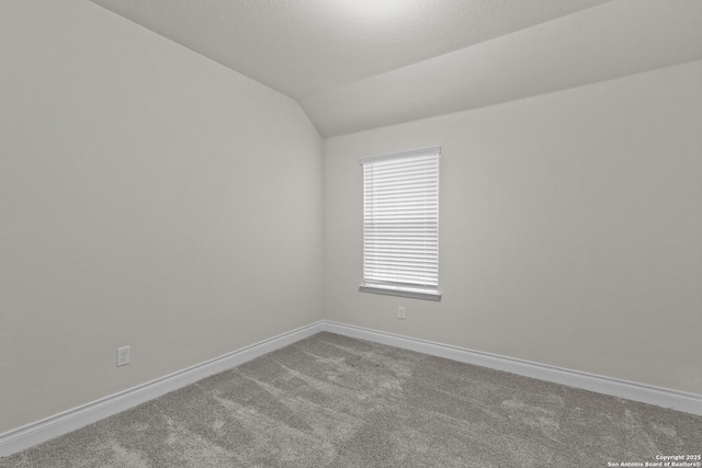 carpeted spare room featuring lofted ceiling