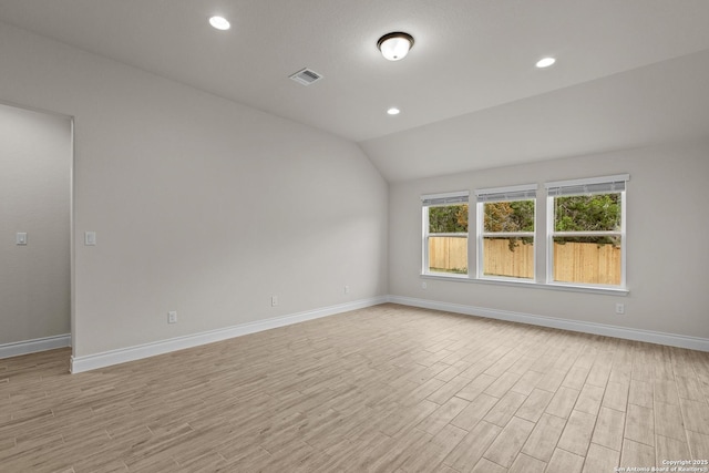 spare room featuring vaulted ceiling and light hardwood / wood-style flooring