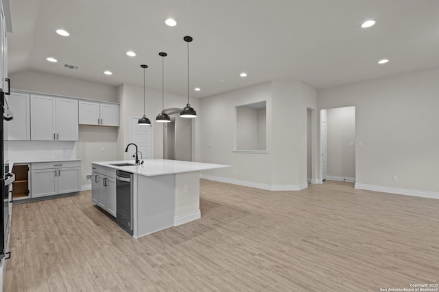 kitchen with sink, tasteful backsplash, light hardwood / wood-style flooring, an island with sink, and pendant lighting