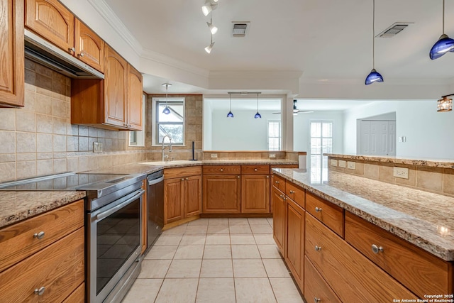 kitchen with sink, appliances with stainless steel finishes, light stone countertops, decorative backsplash, and decorative light fixtures