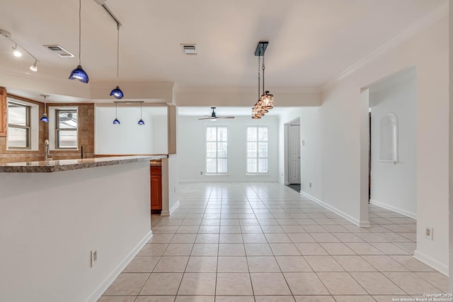 kitchen featuring light tile patterned flooring, hanging light fixtures, ornamental molding, ceiling fan, and light stone countertops