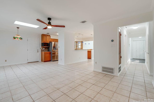 unfurnished living room with light tile patterned floors, a skylight, ornamental molding, and ceiling fan