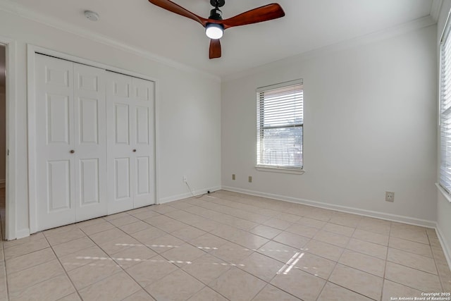 unfurnished bedroom with ornamental molding, light tile patterned floors, ceiling fan, and a closet