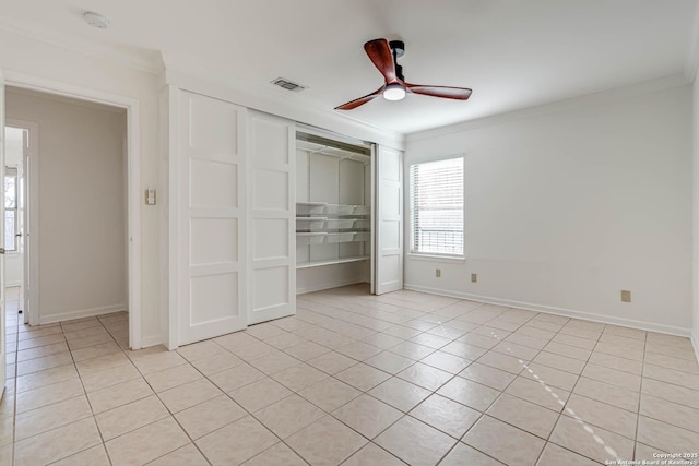 unfurnished bedroom featuring ornamental molding, a closet, ceiling fan, and light tile patterned flooring