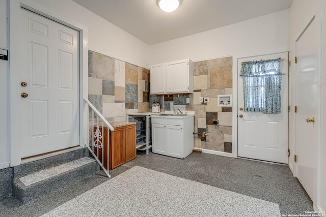 kitchen featuring white cabinetry, sink, and tile walls