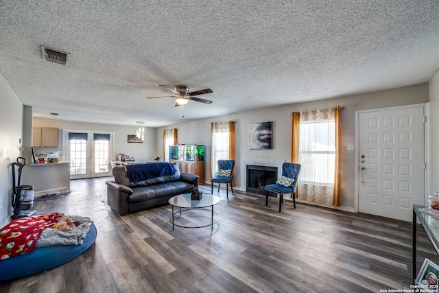 living room with french doors, ceiling fan, dark hardwood / wood-style flooring, and a textured ceiling