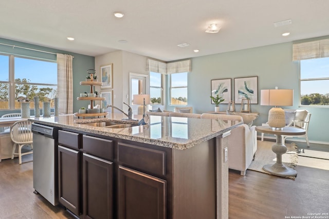 kitchen featuring dark brown cabinetry, sink, light stone counters, dishwasher, and an island with sink