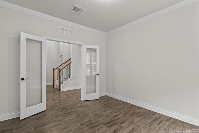 empty room with ornamental molding, a textured ceiling, dark hardwood / wood-style flooring, and french doors