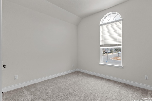 carpeted spare room featuring a healthy amount of sunlight and vaulted ceiling