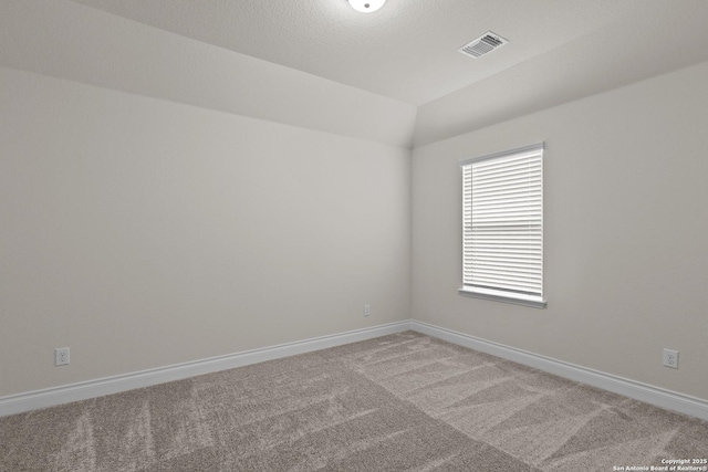 carpeted empty room with lofted ceiling