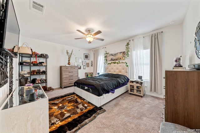 carpeted bedroom featuring ceiling fan and a textured ceiling