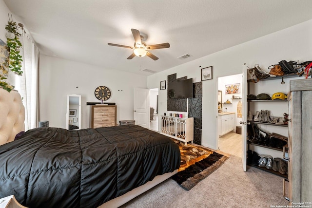 carpeted bedroom featuring ceiling fan, ensuite bathroom, and a textured ceiling