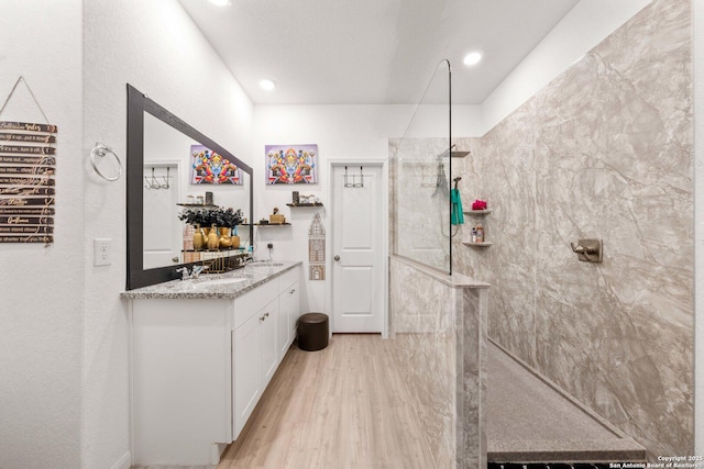 bathroom with vanity, wood-type flooring, and tiled shower