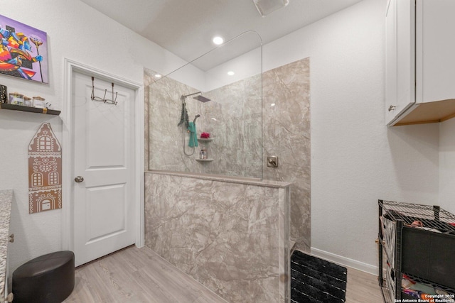 bathroom with tiled shower and hardwood / wood-style floors