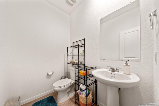 bathroom featuring sink, hardwood / wood-style flooring, vaulted ceiling, and toilet