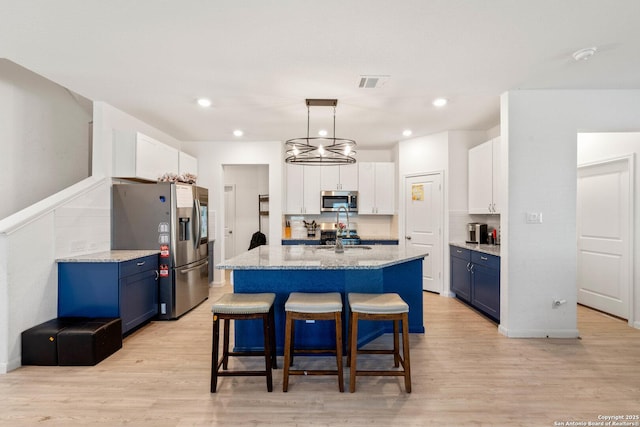 kitchen featuring blue cabinets, decorative light fixtures, a kitchen island with sink, and appliances with stainless steel finishes