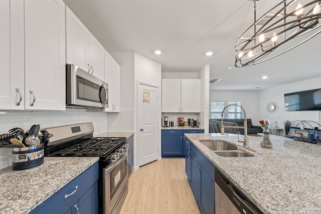 kitchen featuring blue cabinets, sink, decorative light fixtures, appliances with stainless steel finishes, and white cabinets