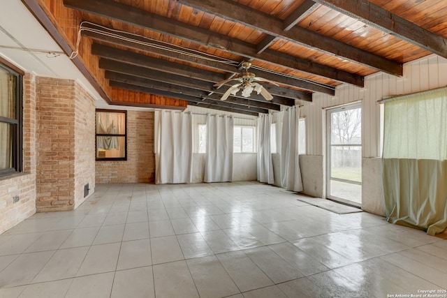 empty room with beamed ceiling, ceiling fan, brick wall, and wooden ceiling