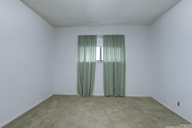 spare room featuring light carpet and a textured ceiling