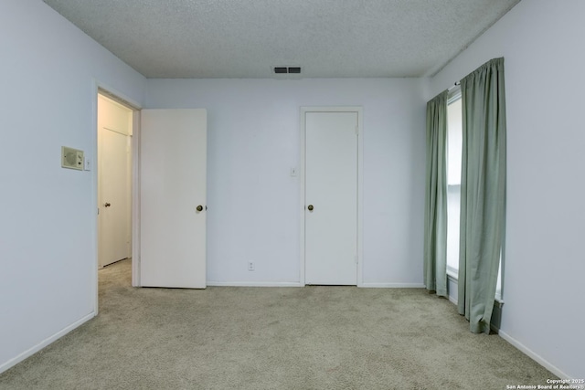 unfurnished bedroom featuring light colored carpet and a textured ceiling