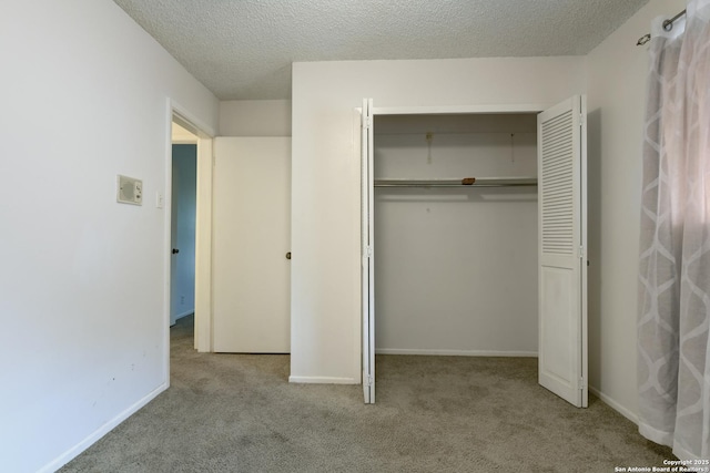 unfurnished bedroom featuring light colored carpet, a textured ceiling, and a closet