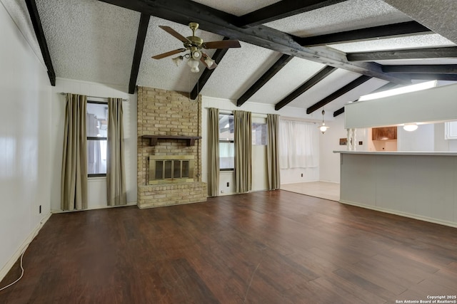 unfurnished living room featuring dark hardwood / wood-style floors, a brick fireplace, lofted ceiling with beams, and a textured ceiling