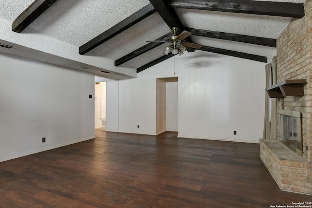 unfurnished living room featuring ceiling fan, dark hardwood / wood-style floors, a fireplace, lofted ceiling with beams, and a textured ceiling