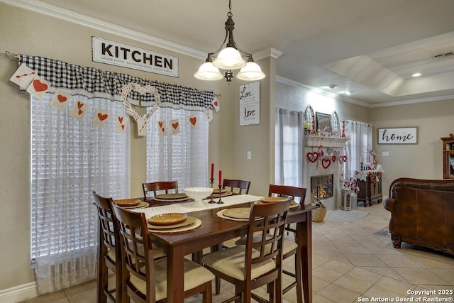 dining room with light tile patterned floors, ornamental molding, and a raised ceiling