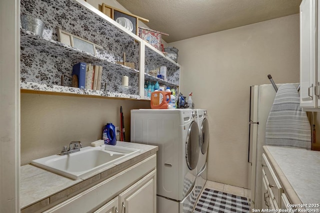 washroom featuring light tile patterned flooring, sink, cabinets, separate washer and dryer, and a textured ceiling