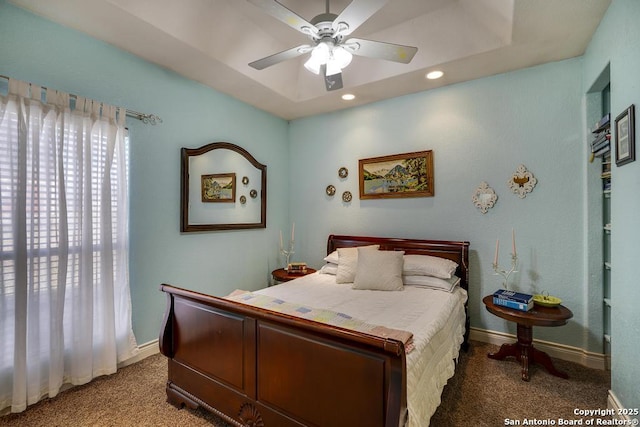 carpeted bedroom featuring a raised ceiling and ceiling fan