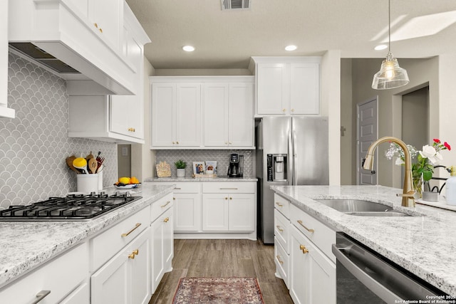 kitchen featuring sink, premium range hood, white cabinetry, backsplash, and appliances with stainless steel finishes