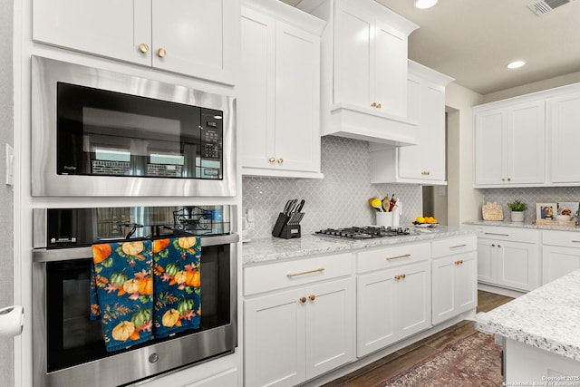 kitchen featuring appliances with stainless steel finishes, white cabinets, dark hardwood / wood-style flooring, and decorative backsplash