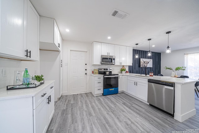 kitchen with stainless steel appliances, white cabinetry, pendant lighting, and kitchen peninsula