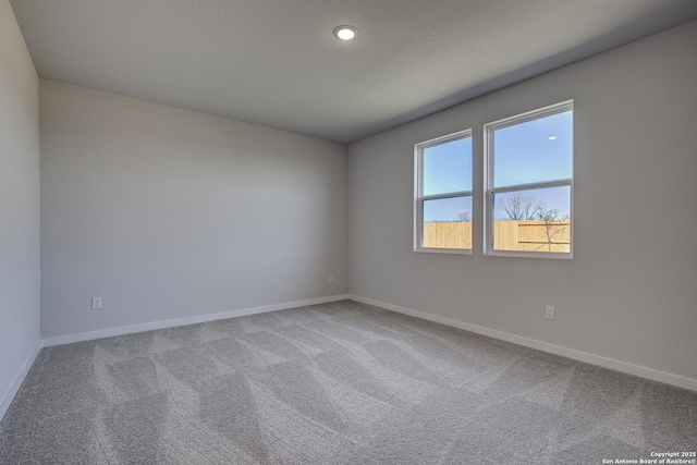 carpeted spare room featuring a textured ceiling, recessed lighting, and baseboards
