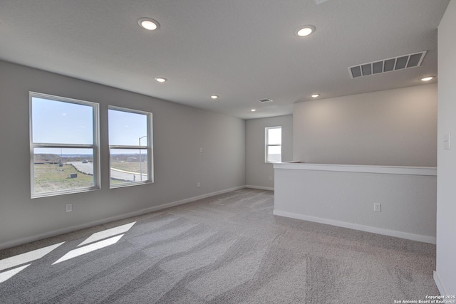 carpeted empty room featuring baseboards, visible vents, and recessed lighting