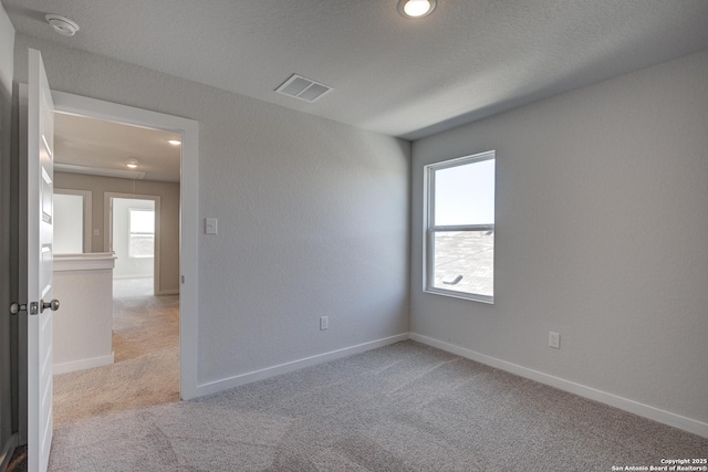 spare room featuring baseboards, carpet, visible vents, and a wealth of natural light