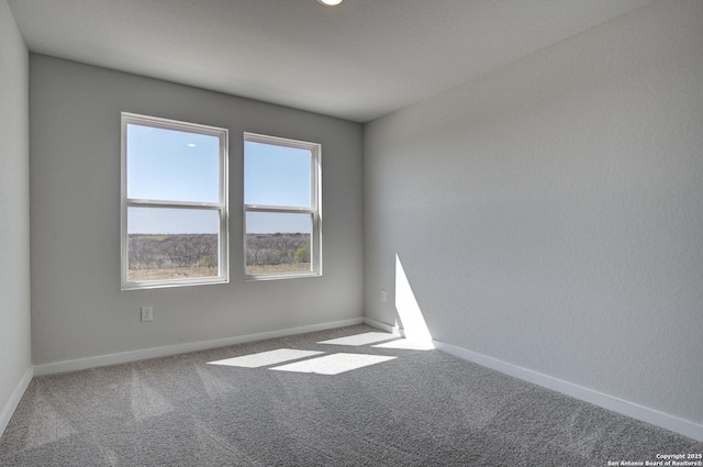 carpeted empty room featuring baseboards