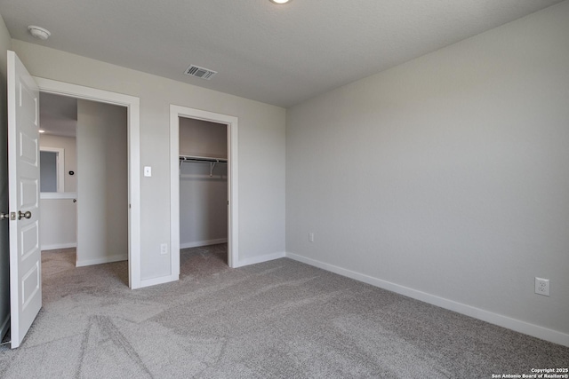 unfurnished bedroom featuring baseboards, visible vents, a spacious closet, carpet flooring, and a closet