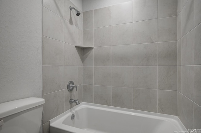 full bath with toilet, bathtub / shower combination, and a textured wall