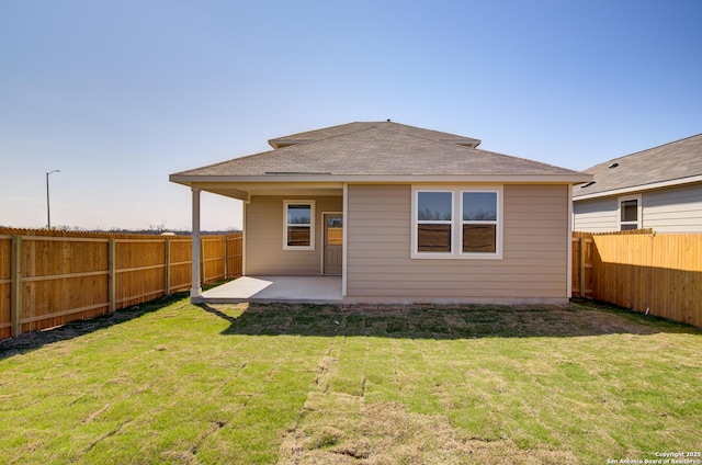 rear view of property with a patio area, a fenced backyard, a shingled roof, and a yard