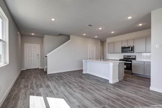 kitchen featuring baseboards, appliances with stainless steel finishes, a sink, gray cabinetry, and backsplash